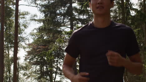 Close-Up-Of-Mid-Adult-Couple-Exercising-Doing-Work-Out-Outdoors-Running-Through-Forest-Towards-Camera-Wearing-Sports-Clothing